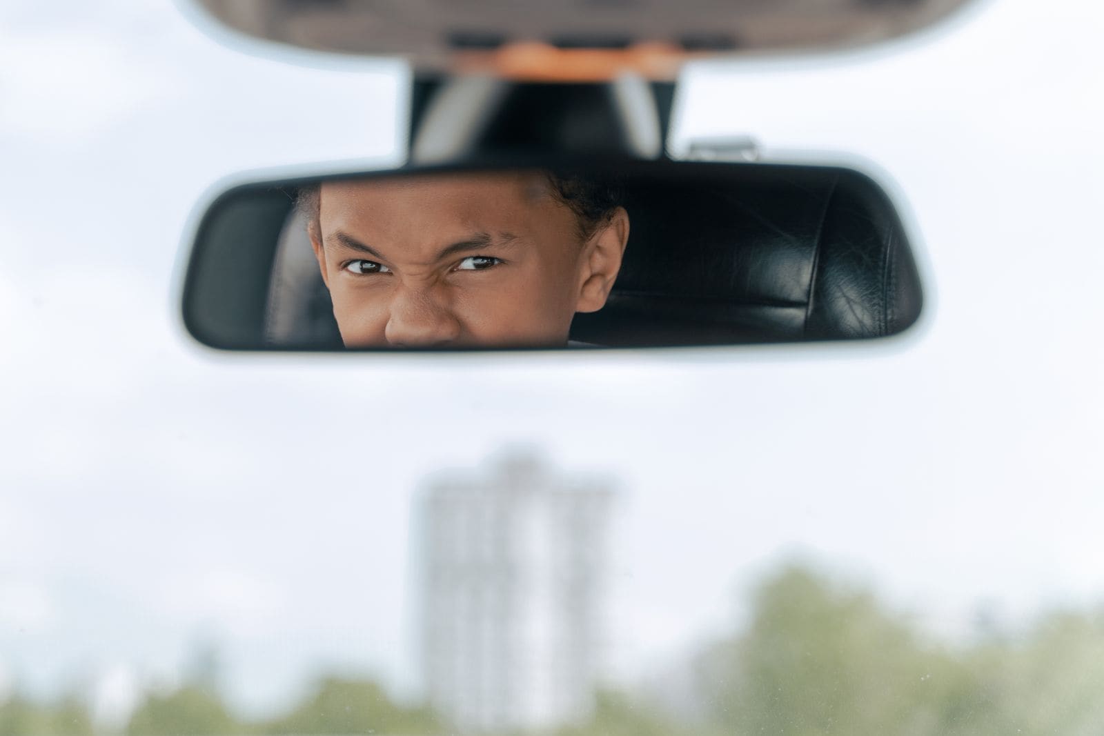 Jovem praticando direção e observando o trânsito pelo retrovisor