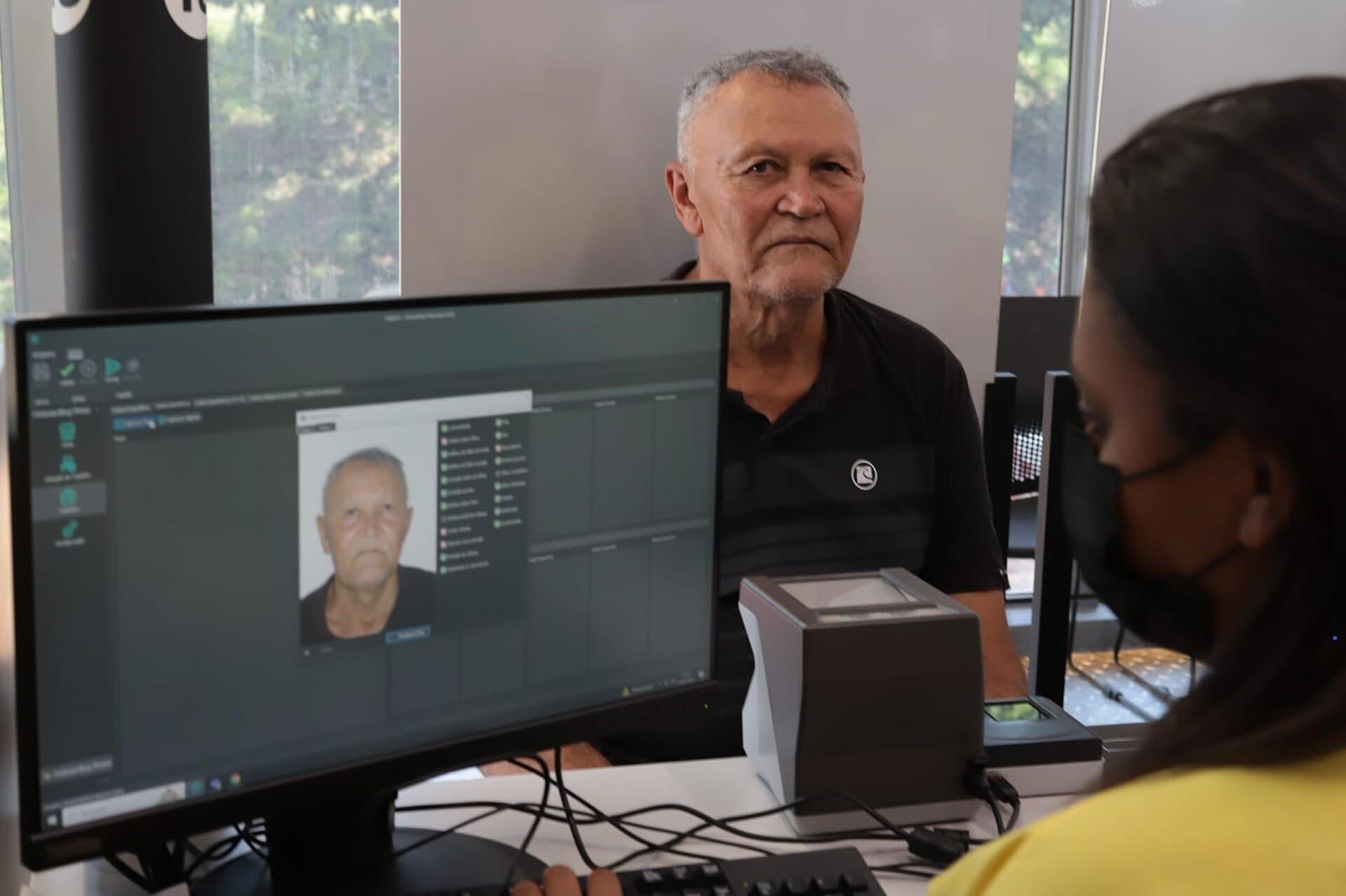 Atendente registra a foto de um cidadão durante a emissão de documento em posto de atendimento no Brasil