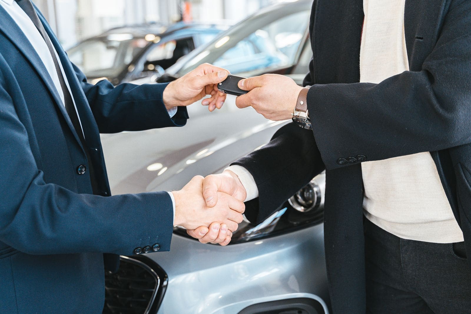 Pessoas trocando a chave de um carro após concluir uma negociação
