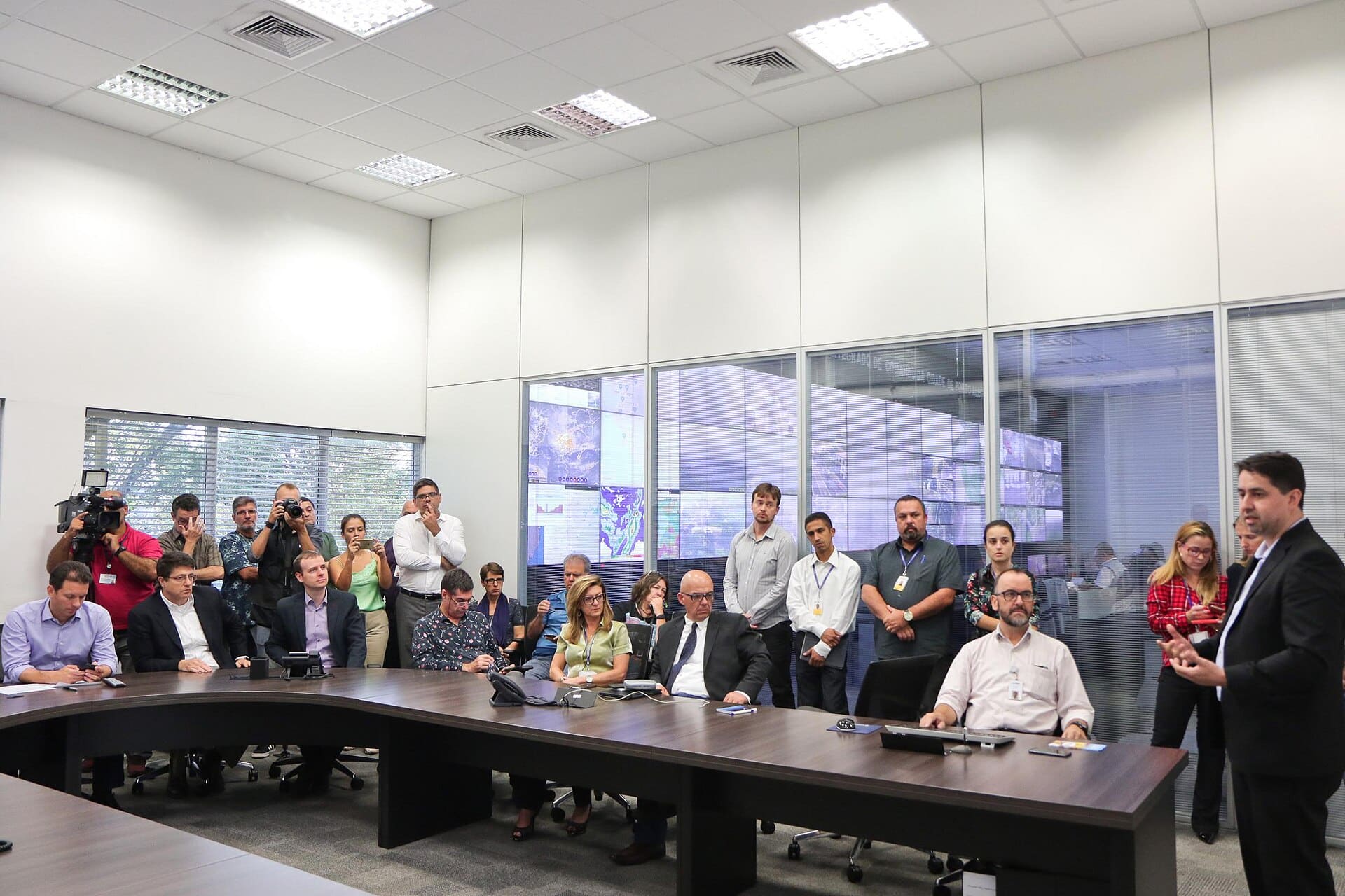 Reunião em sala com equipe acompanhando sistema de monitoramento em telas
