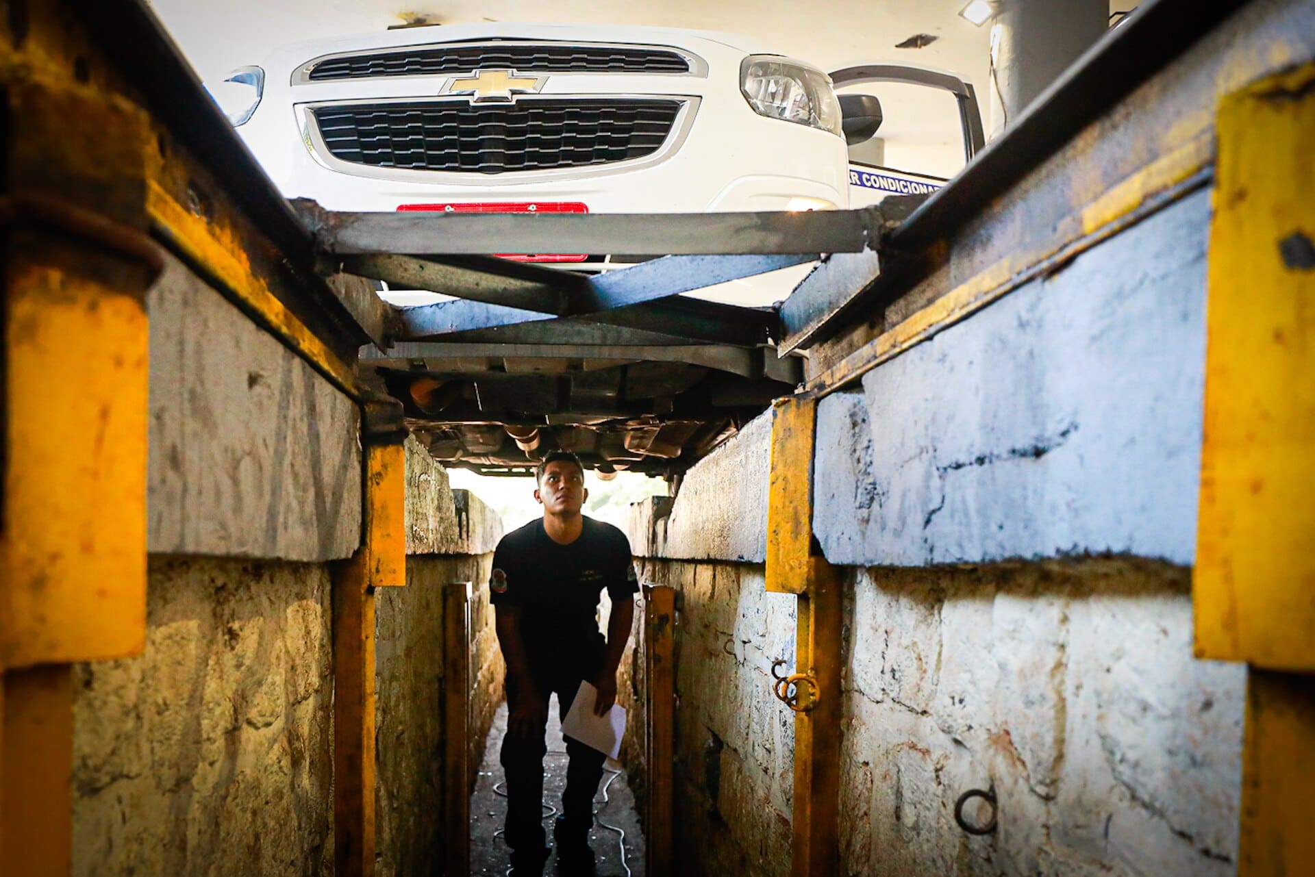 Carro sobre elevador durante inspeção veicular em centro de vistoria no Brasil