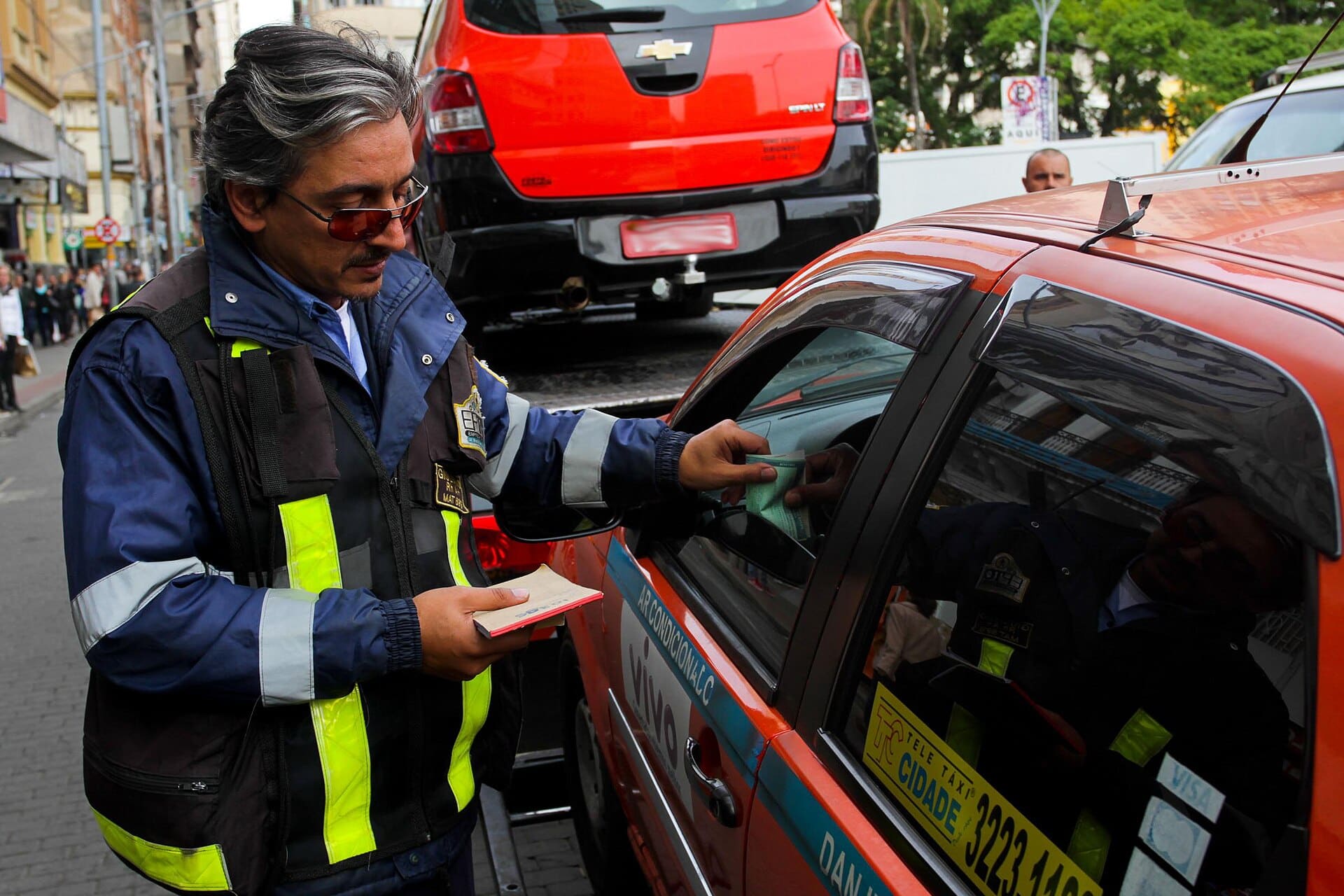 Agente de trânsito registra notificação no para-brisa de veículo em situação irregular