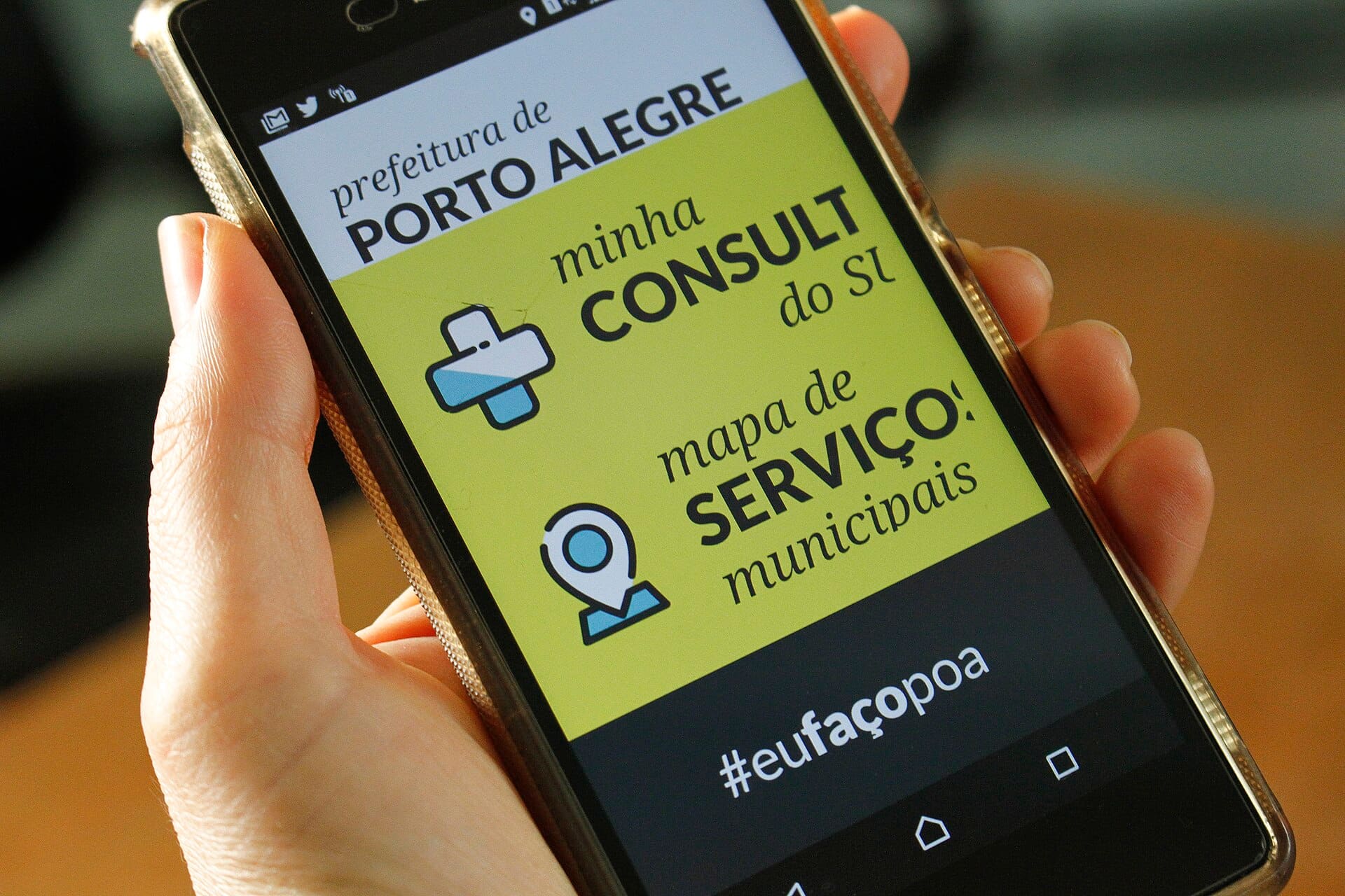 Mão segurando celular com aplicativo de serviços públicos aberto